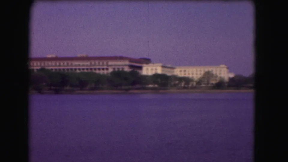 1975 Washington, DC 8mm frame showing a wide waterway with distant institutional buildings, trees, and purple-shifted sky.