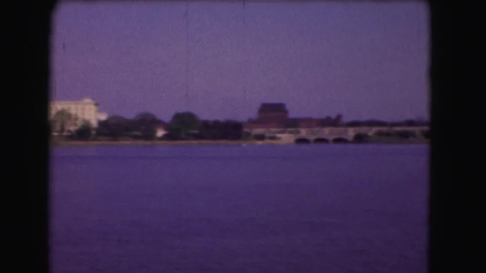 1975 Washington, DC 8mm frame showing the river, a low bridge, trees, and distant civic buildings during the pan.