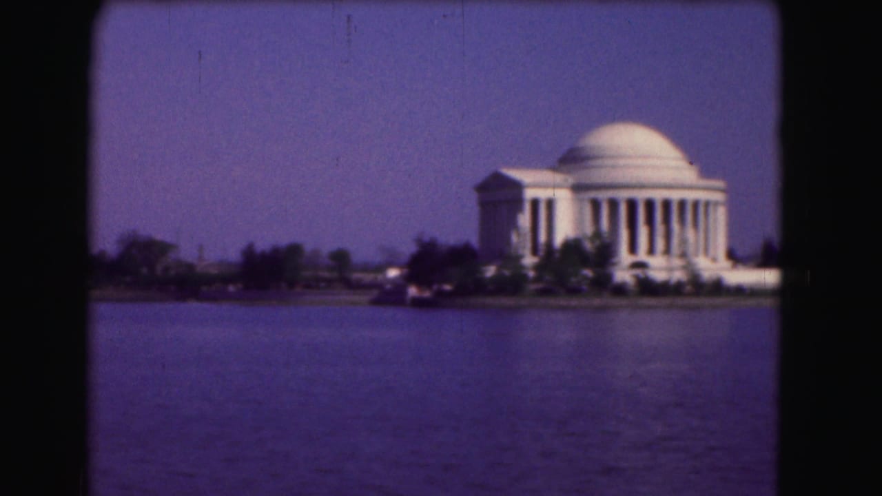 Jefferson Memorial across the Tidal Basin with trees along the shore.