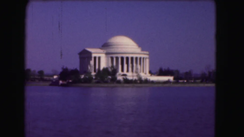 1975 8mm frame with the Jefferson Memorial centered beyond the Tidal Basin, softened by film grain and color shift.