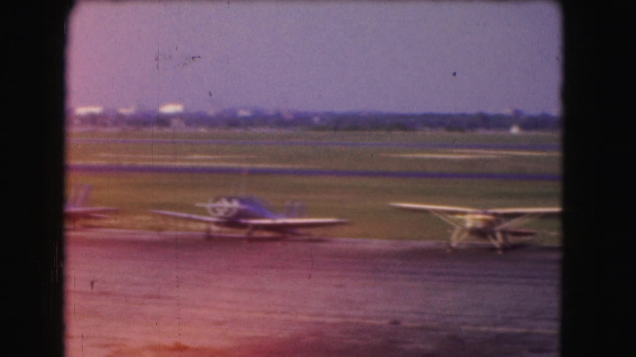 Blue and yellow propeller planes parked on an airfield tarmac under a clear sky.