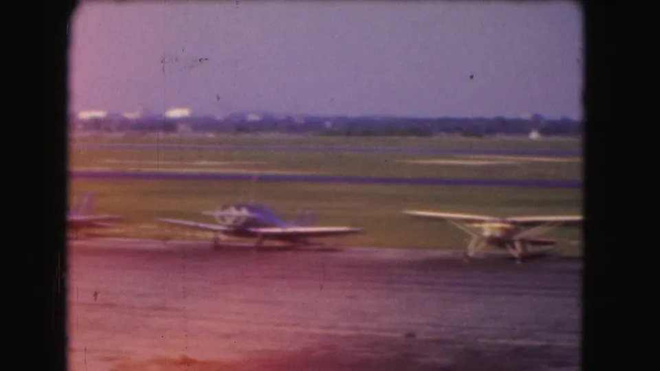 1975 Washington, DC frame with blue and yellow small propeller aircraft parked on the airfield tarmac.