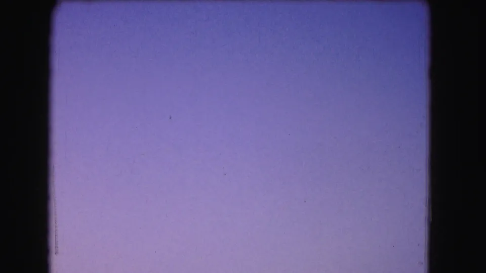 Abstract violet twilight sky from a 1975 Washington, DC 8mm home-movie scan, bordered by dark film edges and light surface marks.