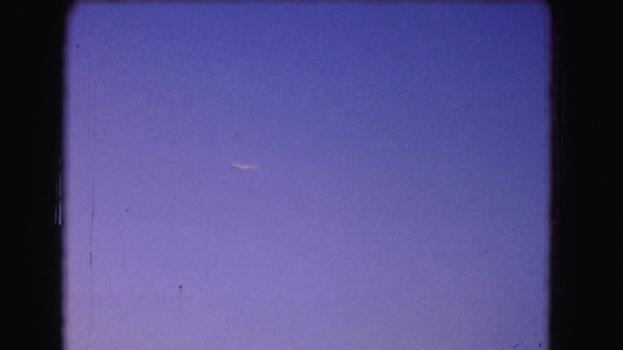 A small airplane appears in a purple dusk sky in 1975 8mm Washington, DC home-movie footage.