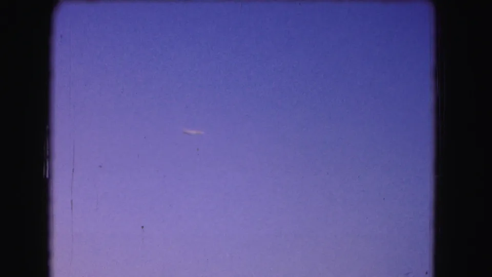 A small airplane appears in a purple dusk sky in 1975 8mm Washington, DC home-movie footage.