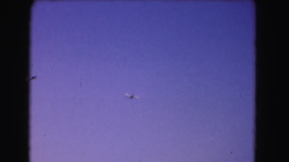 The aircraft remains distant against the darkening Washington, DC sky, framed by 8mm gate edges.