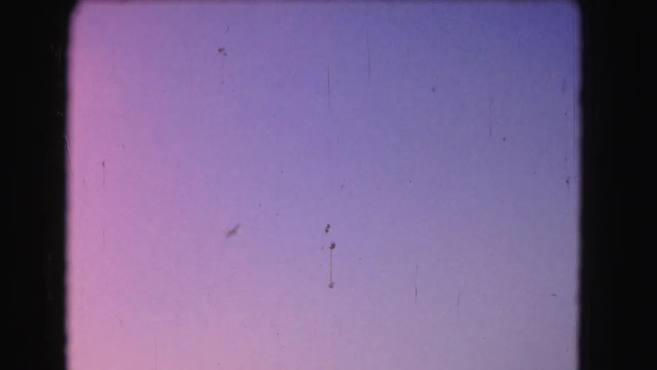 A mostly empty dusk sky shows 8mm grain, scratches, and gate edges between aircraft and landmark views.