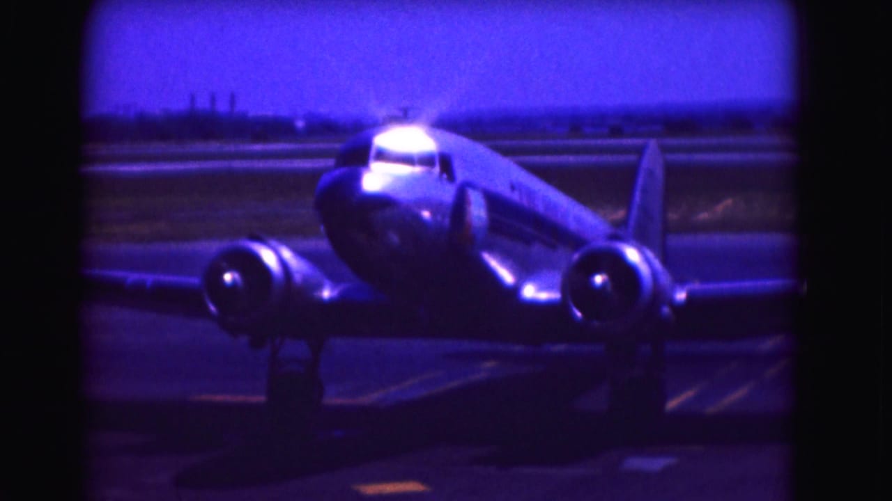 Twin-engine propeller airplane facing the camera on an airport tarmac.