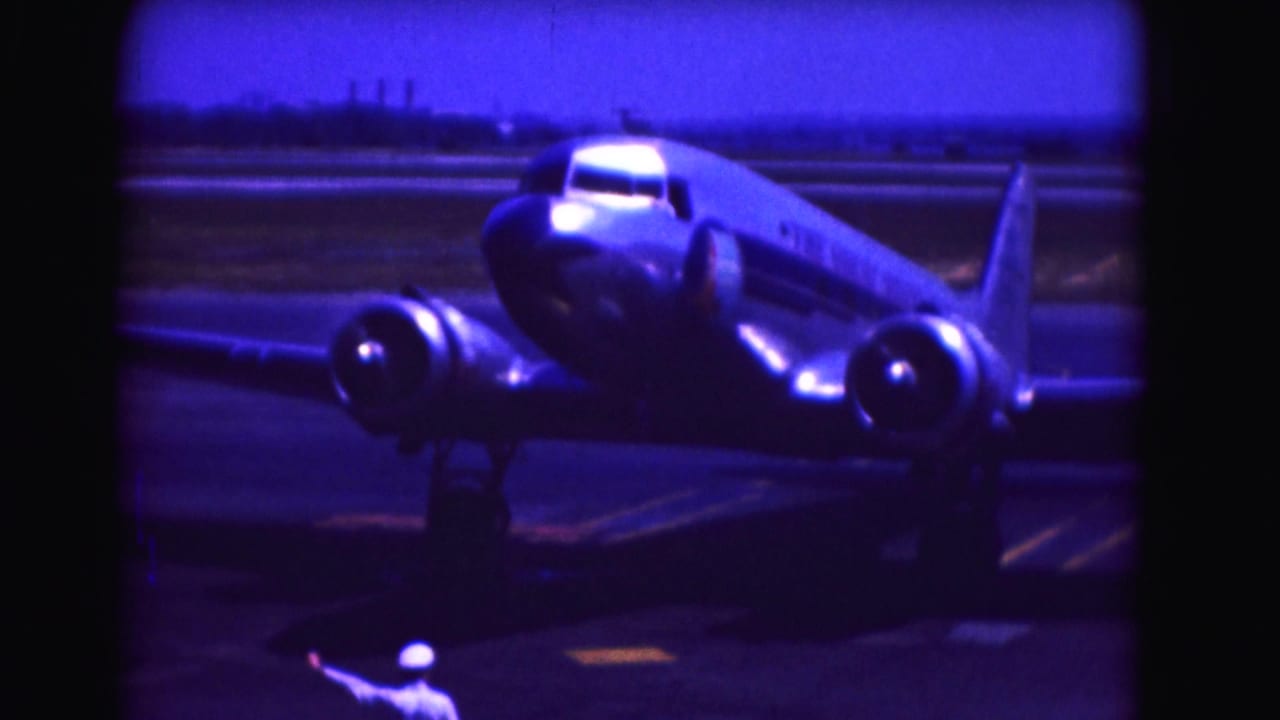 Ground crew member signals near a twin-engine airplane on the tarmac.