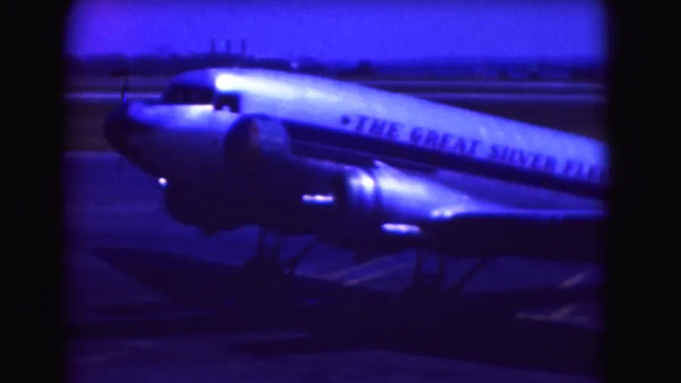 1975 Washington, DC-area frame showing the side of a twin-engine propeller airplane with visible fleet lettering on the fuselage.
