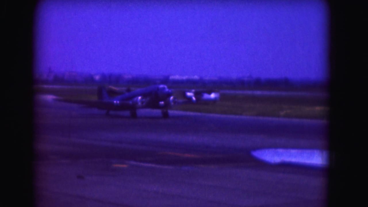 Propeller airplane taxiing on a runway beneath a deep blue sky.