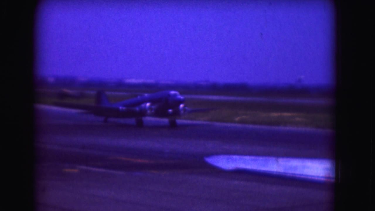 Propeller airplane continues taxiing across the airport runway.