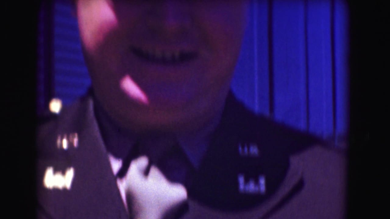 1975 8mm close-up of a U.S. military officer in uniform adjusting his tie near an airport or air base observation area.