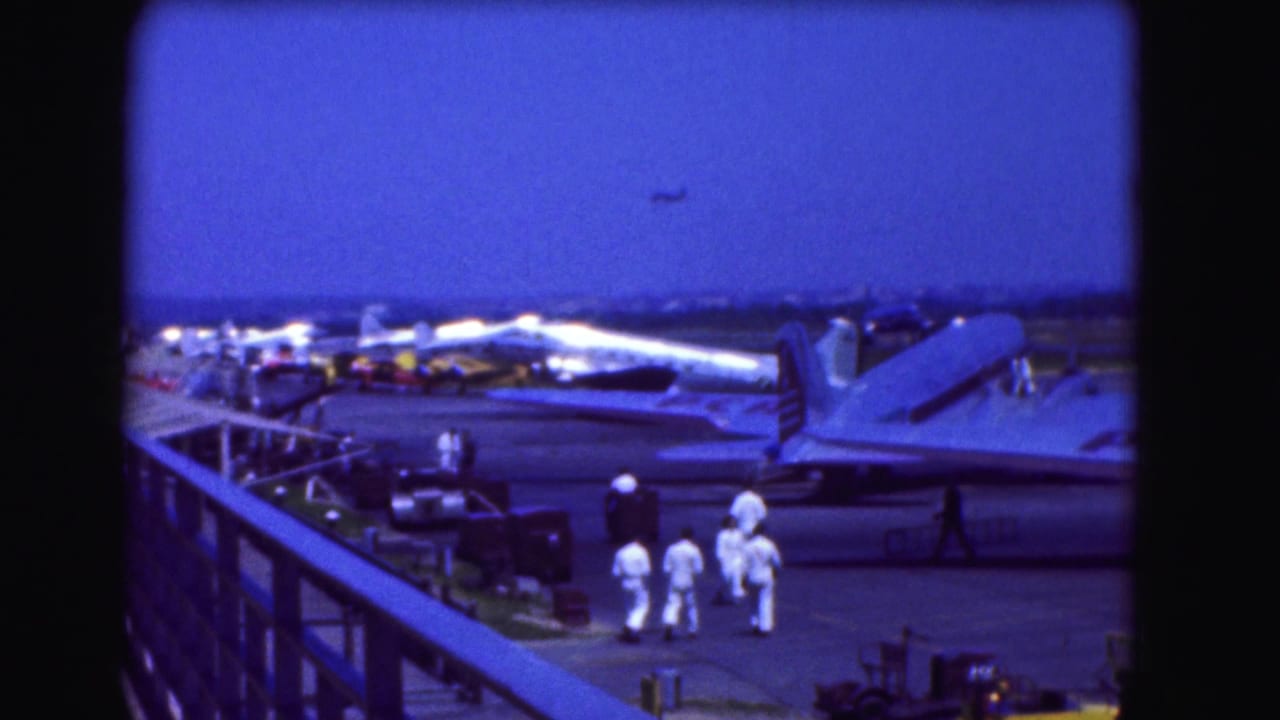 Aircraft parked on a tarmac with ground crew below an observation railing.