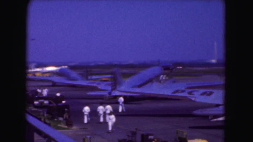 1975 Washington DC airport view with several aircraft on the apron and white-uniformed crew gathered near the planes.
