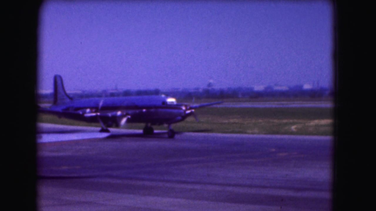 Large propeller airplane taxiing on a tarmac with runway grass behind it.