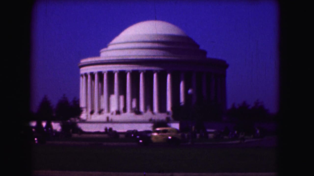 Jefferson Memorial under a deep blue sky with cars and visitors in front.