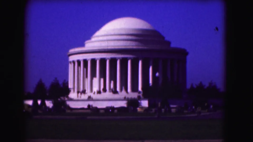 1975 Washington, DC home-movie frame showing the Jefferson Memorial, foreground lawn, cars, trees, and small visitors.