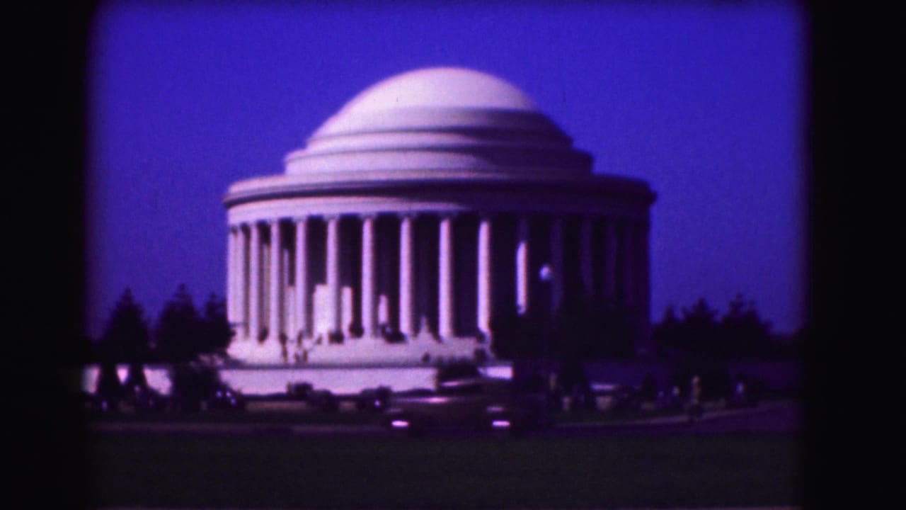 Jefferson Memorial at dusk with cars passing in the foreground.