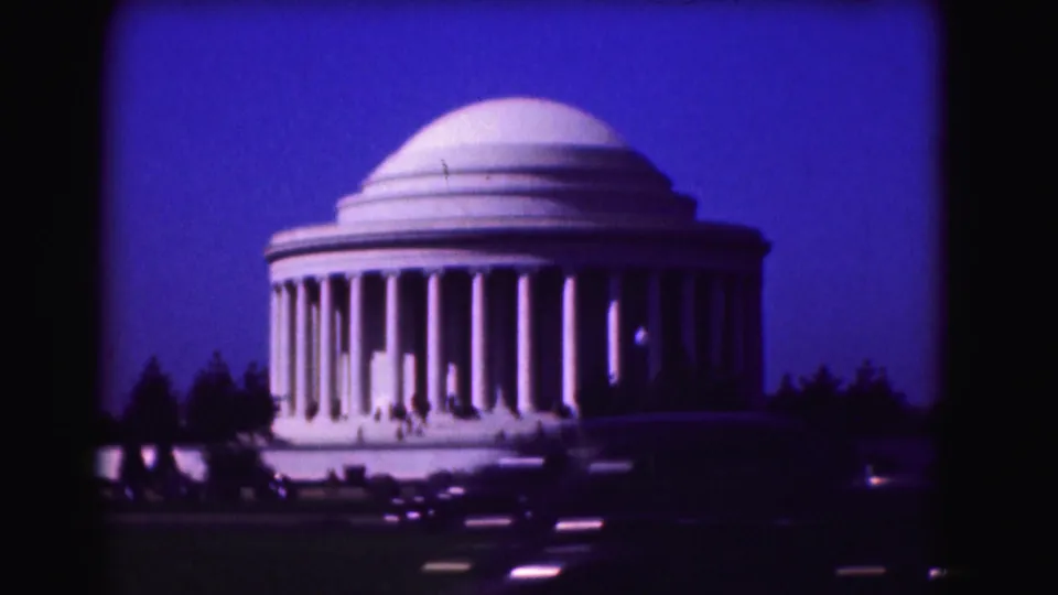 1975 Washington, DC home-movie frame of the Jefferson Memorial centered against twilight with traffic headlights in the foreground.