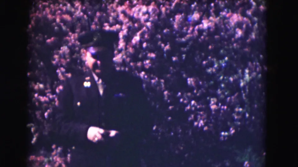 At the end of the clip, the Washington DC officer turns slightly while standing before the flowering tree.