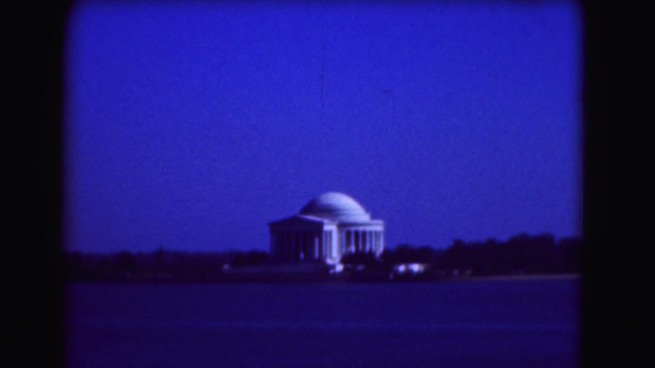Jefferson Memorial across dark water under a deep blue night sky.
