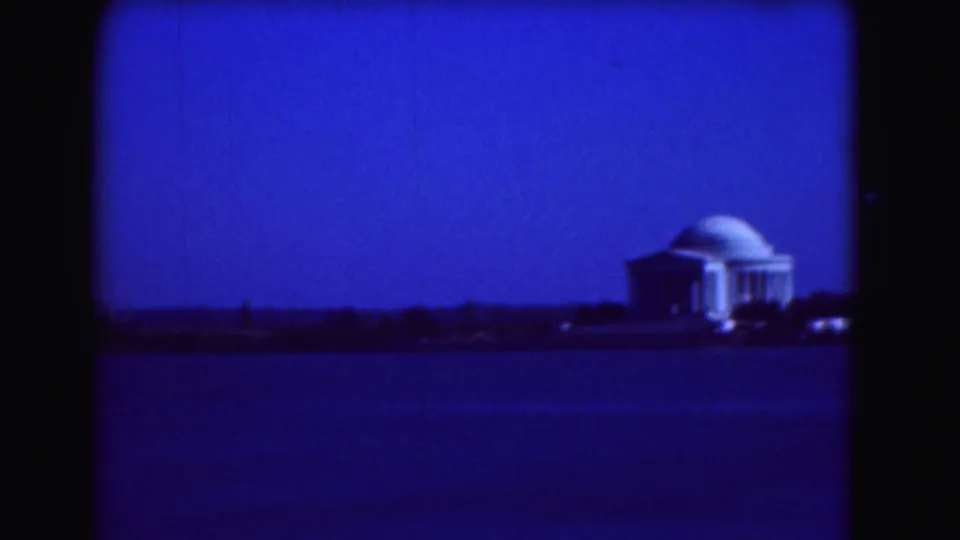 1975 Washington DC home-movie frame with the Jefferson Memorial seen across the Tidal Basin under a deep blue cast.