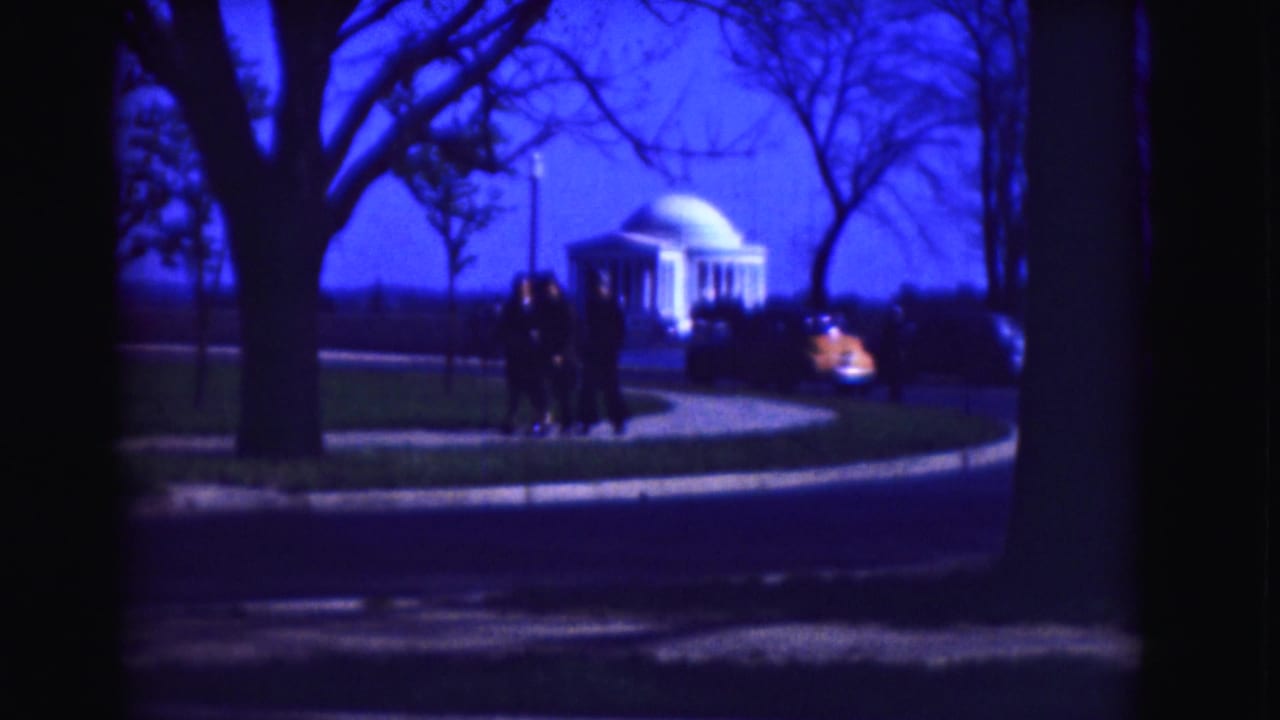 Pedestrians near a curved roadway with the Jefferson Memorial visible through trees.