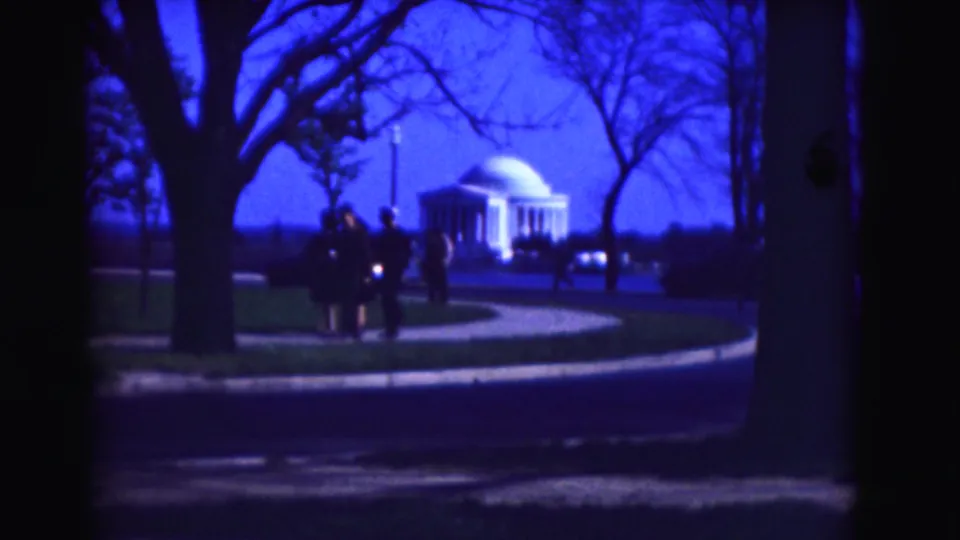 1975 Washington, DC frame with visitors near a sidewalk, tree trunks in the foreground, and the Jefferson Memorial across the roadway.