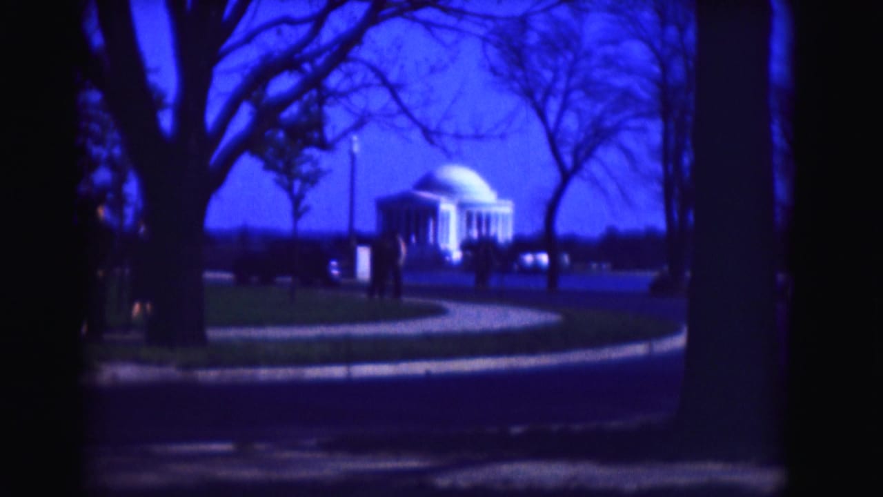 Jefferson Memorial framed by bare trees and a curving path under a deep blue sky.