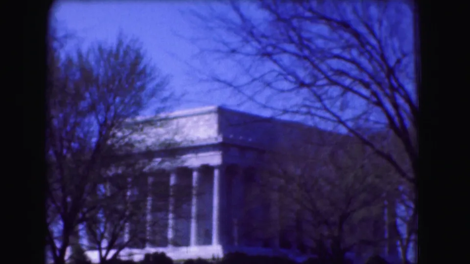 The Lincoln Memorial is held in a soft 8mm frame with leafless branches crossing the blue sky.