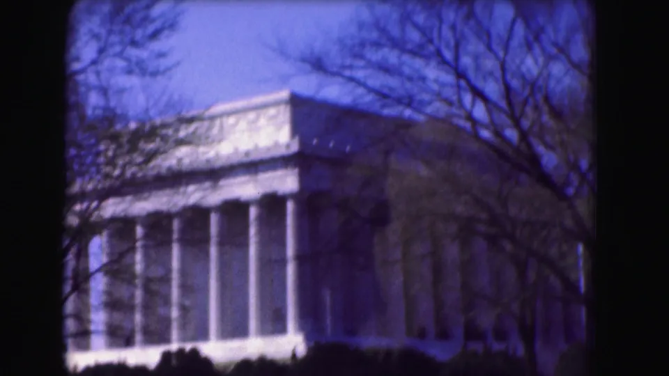 1975 Washington, DC frame of the Lincoln Memorial exterior, with columns, pediment detail, leafless branches, and deep blue sky.