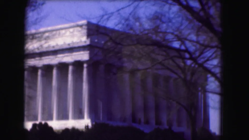 1975 Washington, DC home-movie frame showing a closer angled view of the Lincoln Memorial columns with branches crossing the foreground.