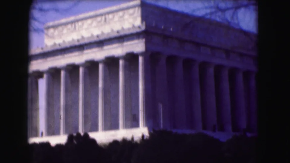 1975 8mm view of the Lincoln Memorial in Washington, D.C., framed close with columns, roofline, shrub shadows, and a purple film cast.