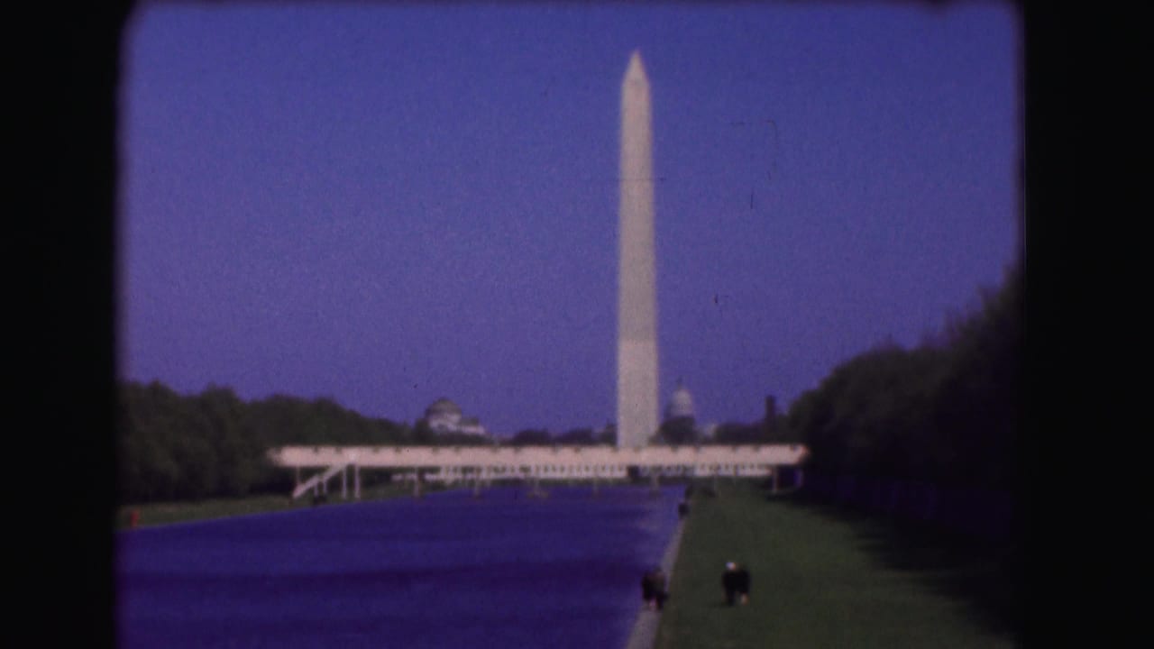Washington Monument beyond the Reflecting Pool with lawns and trees.