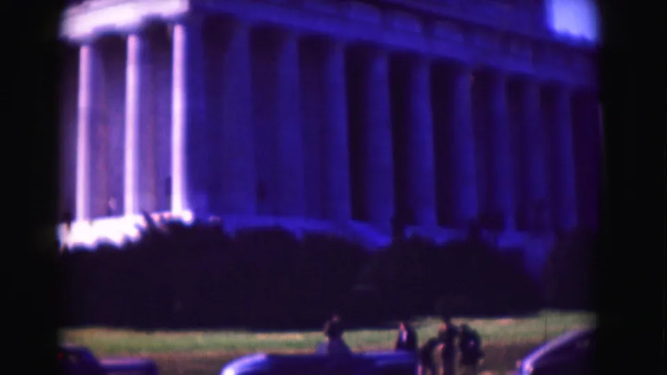 1975 8mm view of the Lincoln Memorial in Washington, D.C., with columns, lawn, period cars, and small visitors in frame.