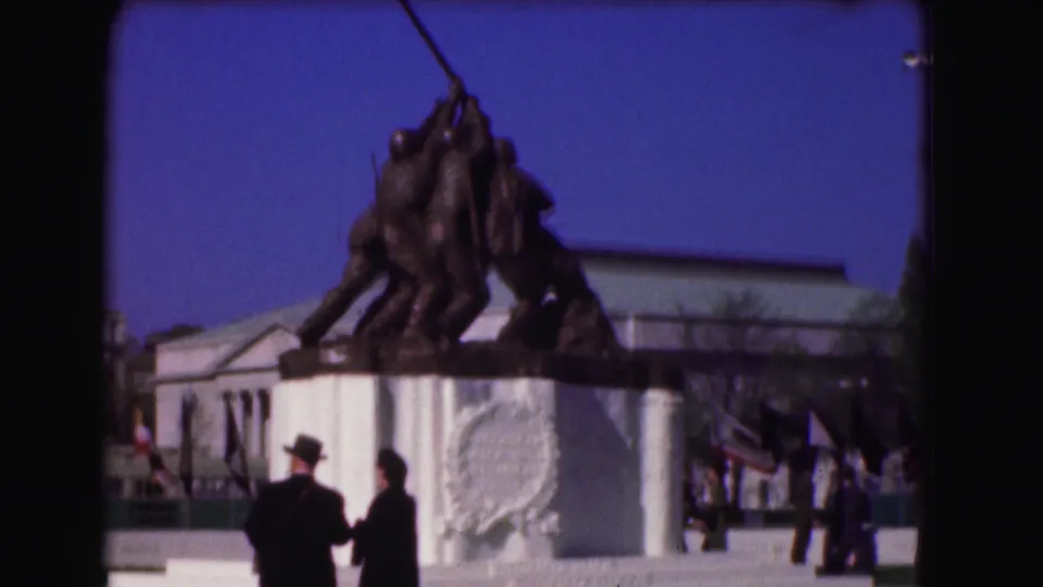 Home-movie view of the Marine Corps War Memorial in the Washington area, showing the statue, pedestal, visitors, and flags.