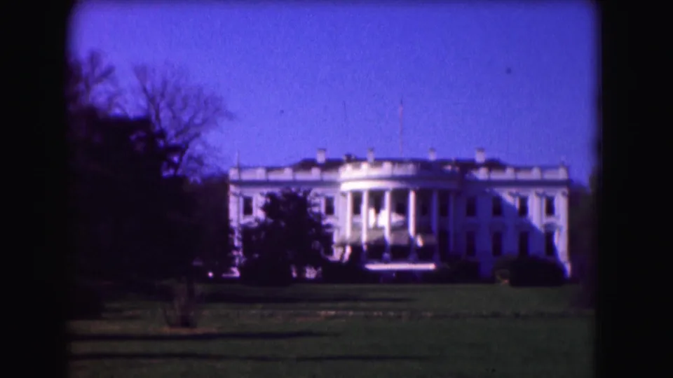 1975 home-movie frame showing the White House and lawn in Washington, D.C., with dark trees along both sides.