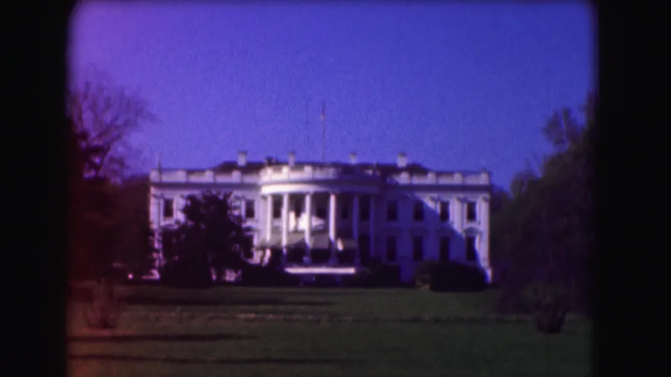 1975 8mm view of the White House in Washington, DC, seen from across the lawn with trees framing the building.