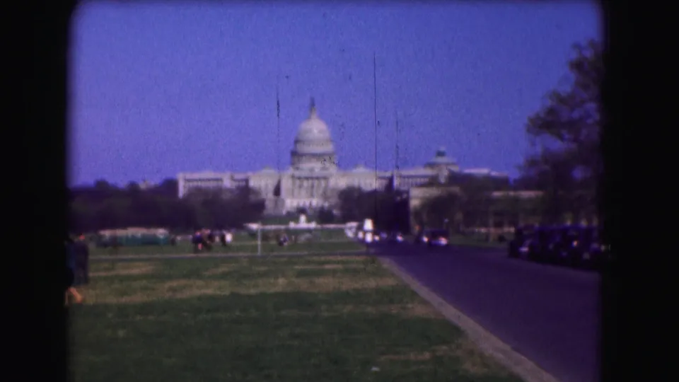 1975 8mm view toward the U.S. Capitol in Washington, DC, across a broad lawn with cars along the road.