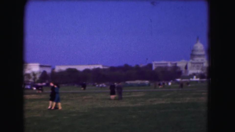 Soft 8mm frame from Washington, D.C. showing the Capitol partly off to the right as visitors cross the Mall lawn.
