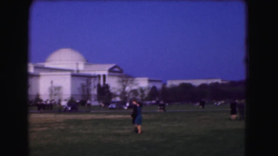 1975 Washington, D.C. home-movie frame showing a large domed neoclassical building near the Mall, with pedestrians and traffic in the foreground.