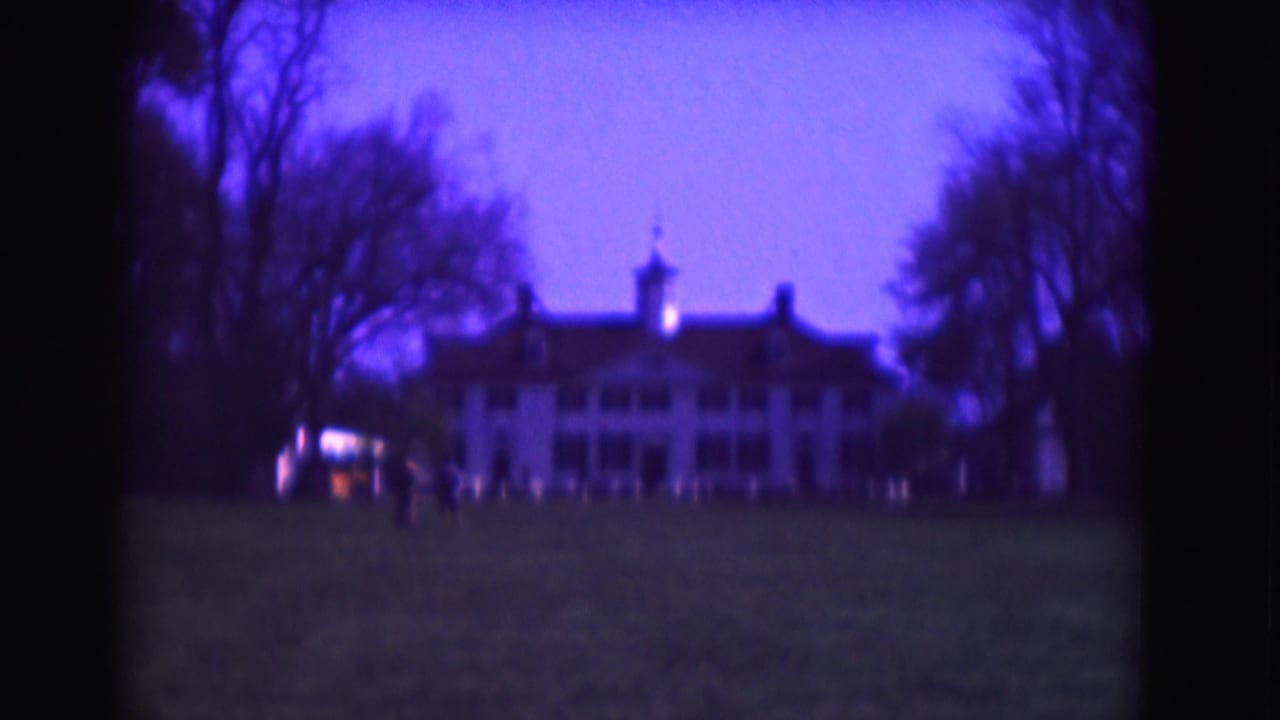 1975 Washington, DC home-movie frame with a grand white building, silhouetted trees, open grass, and distant people near the entrance area.