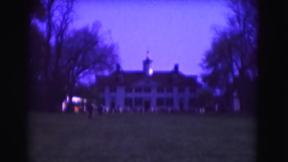 1975 Washington, DC home-movie frame with a grand white building, silhouetted trees, open grass, and distant people near the entrance area.