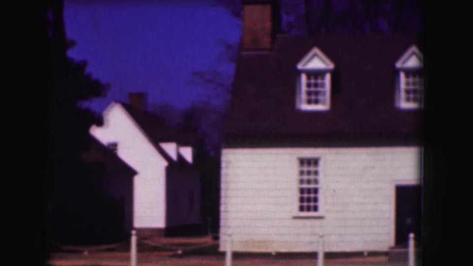 Soft 8mm frame of white historic-house exteriors in Washington, DC, with dormer windows, dark roofs, a chimney, and roped posts.
