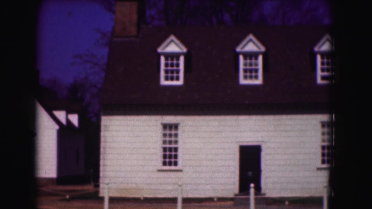 White clapboard house with dormer windows under a dark purple sky.