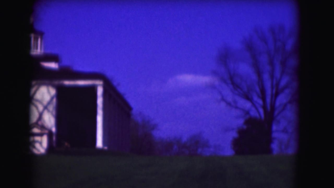 1975 8mm Washington, DC frame showing a white residence side view with cupola, lawn, bare trees, and a strong blue color cast.