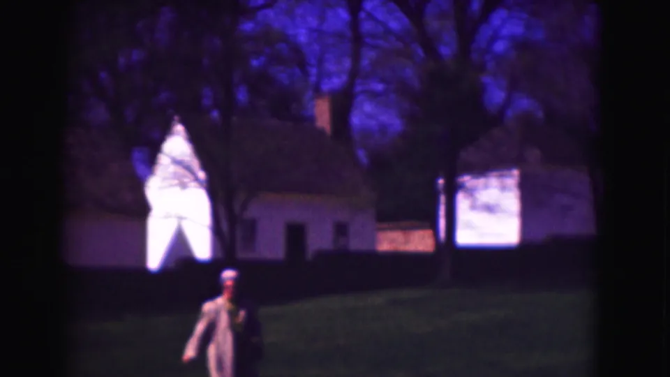 1975 Washington DC frame showing a uniformed adult near the lower edge while buildings and trees fill the background.
