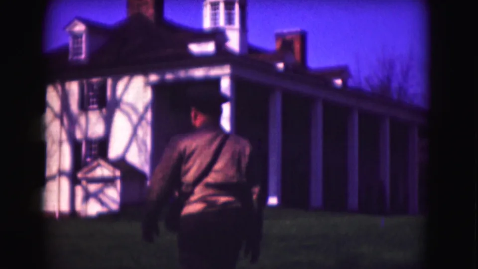 Uniformed adult man on a Washington DC lawn in 1975, with a white historic-style building and long colonnade in the background.
