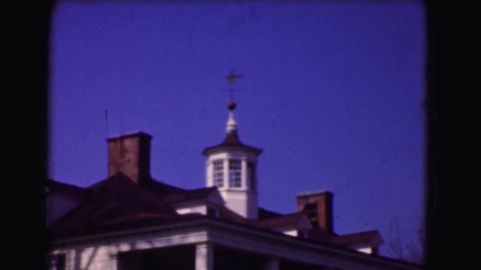 A tighter 8mm view shows the colonial-style roofline, cupola, chimneys, and porch columns in the Washington DC exterior footage.